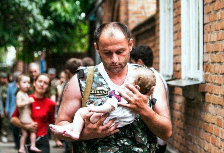 Лейтенант милиции из взвода оперативного реагирования Управления ГИБДД МВД Северной Осетии Эльбрус Гогичаев бережно несёт на руках шестимесячную Алёну Цкаеву. 3 сентября 2004 года